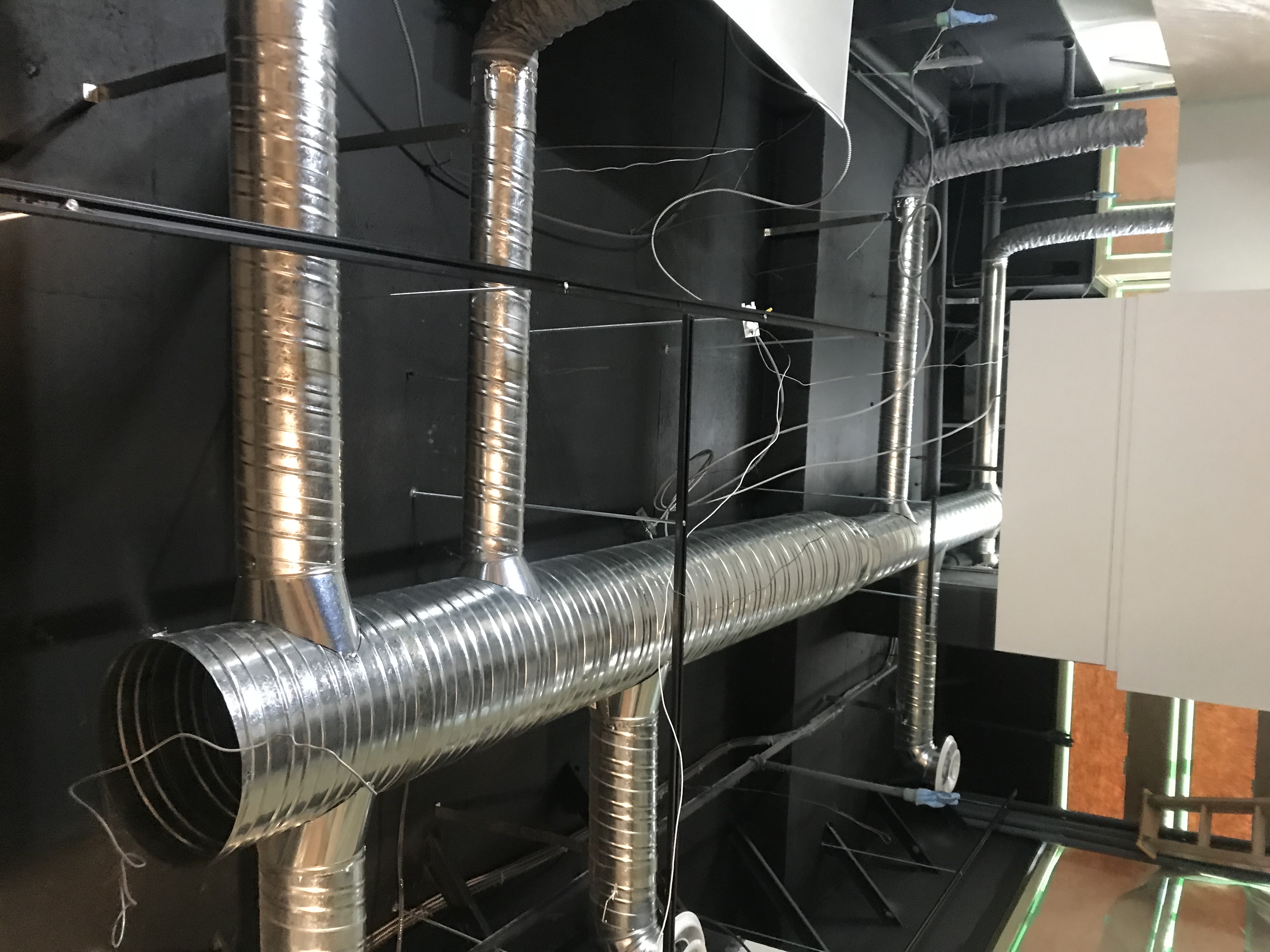Commercial spiral ductwork installed on exposed black ceiling